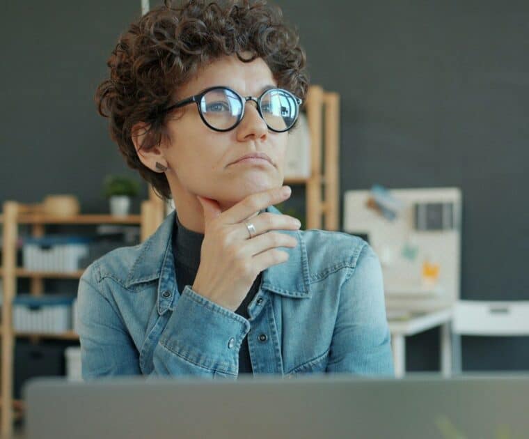 Woman wearing glasses thinking at desk